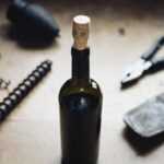 Abrir Vinho Sem Saca Rolha: Mesa com garrafa de vinho, parafuso e alicate, representando o método de emergência.