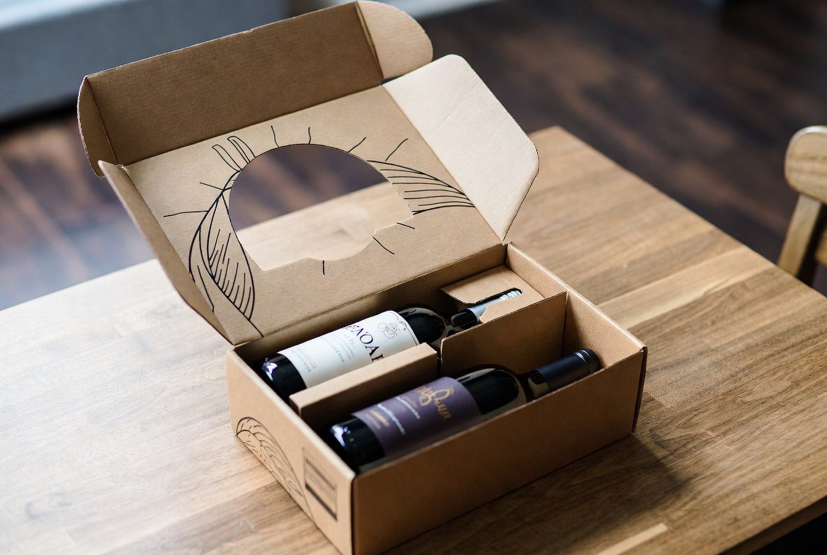 Assinatura de Vinhos: caixa de clube de vinho sendo aberta com garrafas e ficha técnica de degustação.