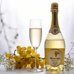 Espumante Moscatel: Garrafa gelada com taça e uvas Moscato, destacando o frescor e a doçura.