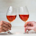 Como Segurar Taça de Vinho: Mão segurando corretamente pela haste versus incorretamente pelo bojo.