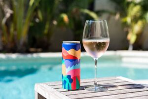 Vinho em Lata: Latinha de vinho rosé gelada ao lado da piscina, demonstrando praticidade e frescor.