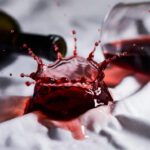 SOS Mancha de Vinho: Vinho tinto atingindo uma camisa branca, demonstrando a urgência da limpeza.
