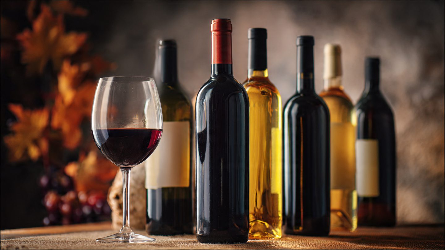 garrafas de vinho acessíveis sobre mesa com taça e iluminação aconchegante