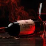 Garrafa de Vinho Casillero del Diablo Cabernet Sauvignon em destaque sobre uma mesa de madeira escura com iluminação dramática e uma taça ao lado.