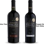 Duas garrafas de Vinho Pérgola (seco e suave) em uma mesa de madeira rústica, com uvas frescas ao lado e luz solar natural.