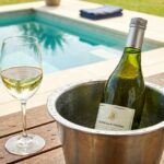 Garrafa de vinho branco Sauvignon Blanc chileno em um balde de gelo na beira da piscina em um dia ensolarado.